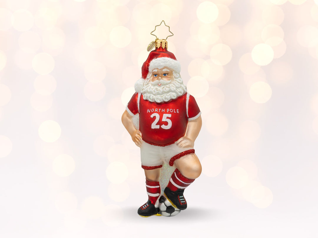 A red and white santa ornament wearing a 25 jersey and resting his foot on a soccer ball.