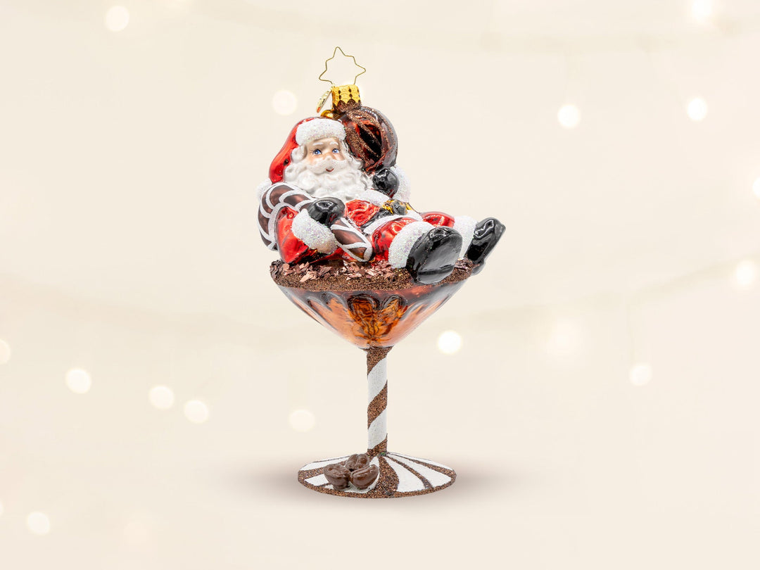A classic red santa ornament sitting in a chocolate martini glass.