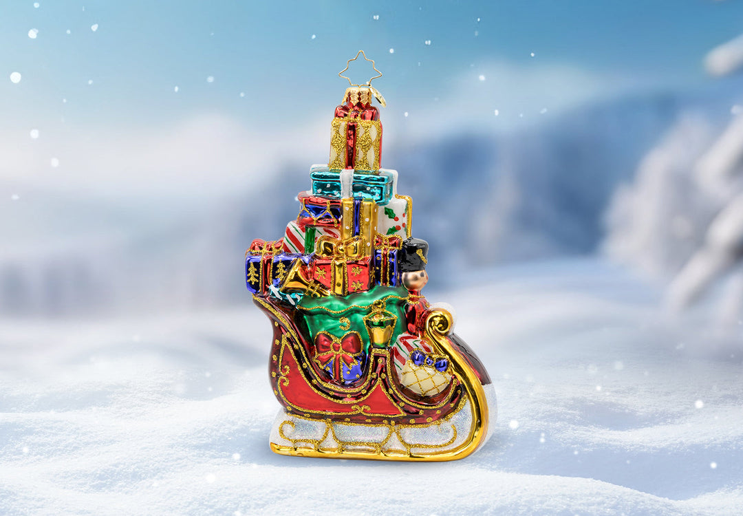 A red sleigh ornament packed full with a tower of wrapped presents.
