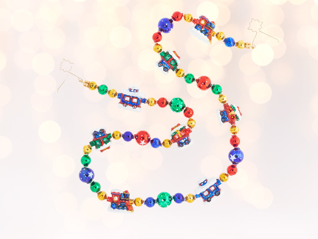 A red, green, blue, and yellow multicolored train garland. Solid colored round baubles seperate the train secions on the garland.