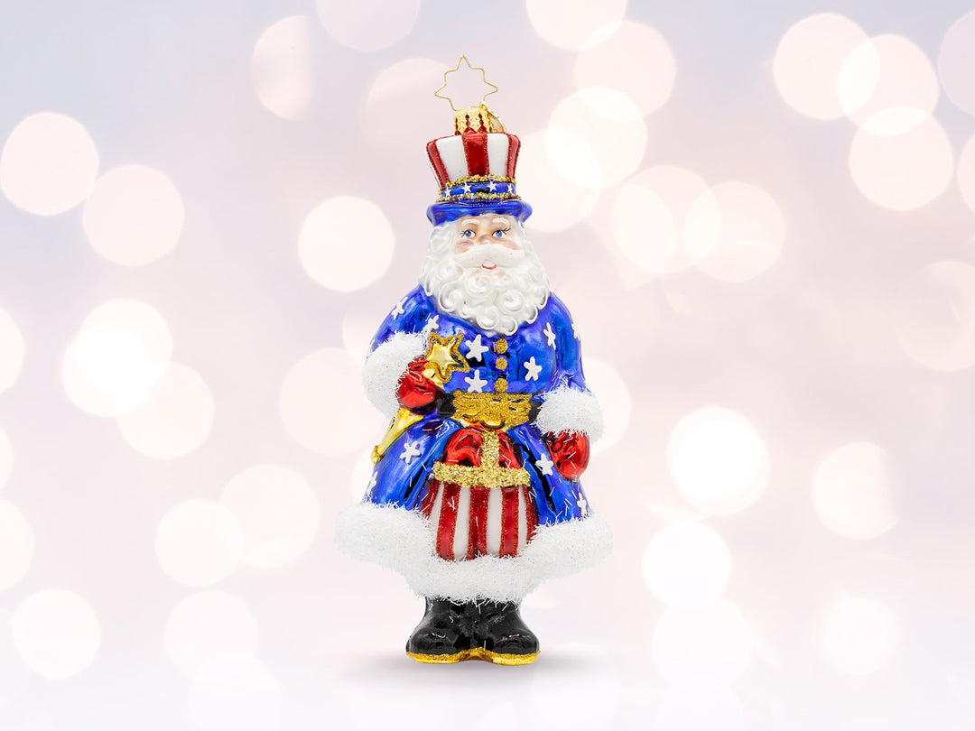 A patriotic American santa ornamnet, wearing a blue star robe, and red white striped pants and hat.