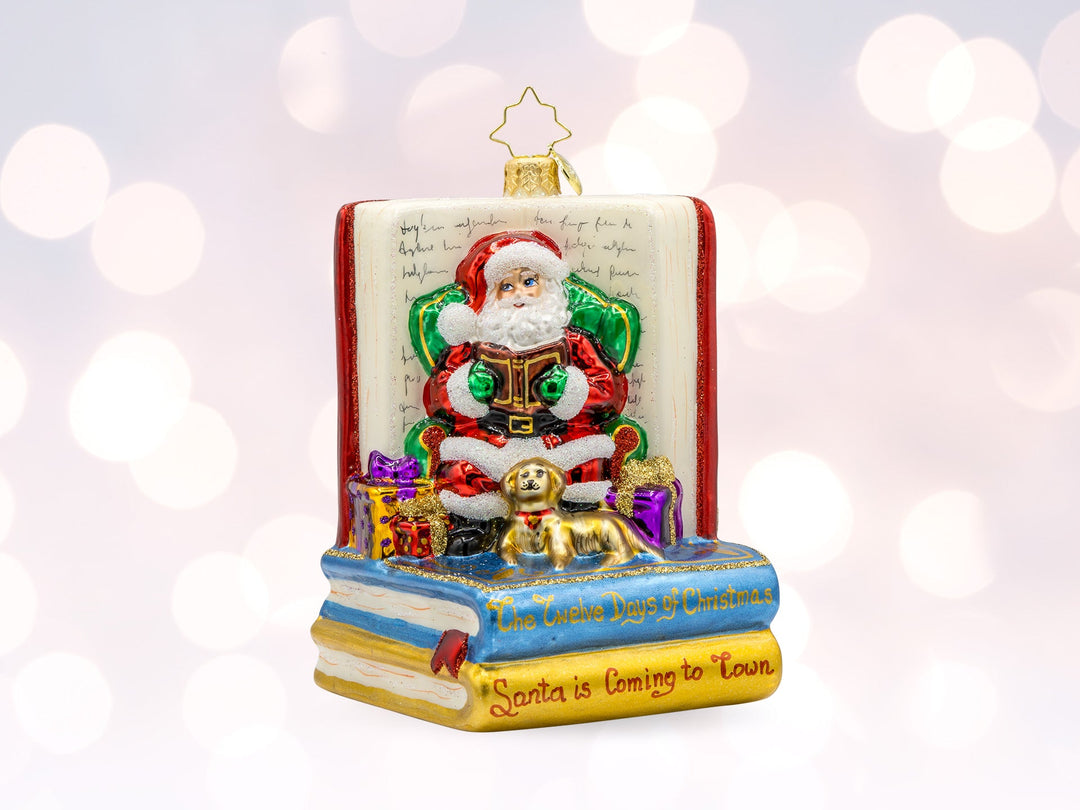A red classic santa ornament sitting in a chair reading a book to a dog on top of a stack of books.