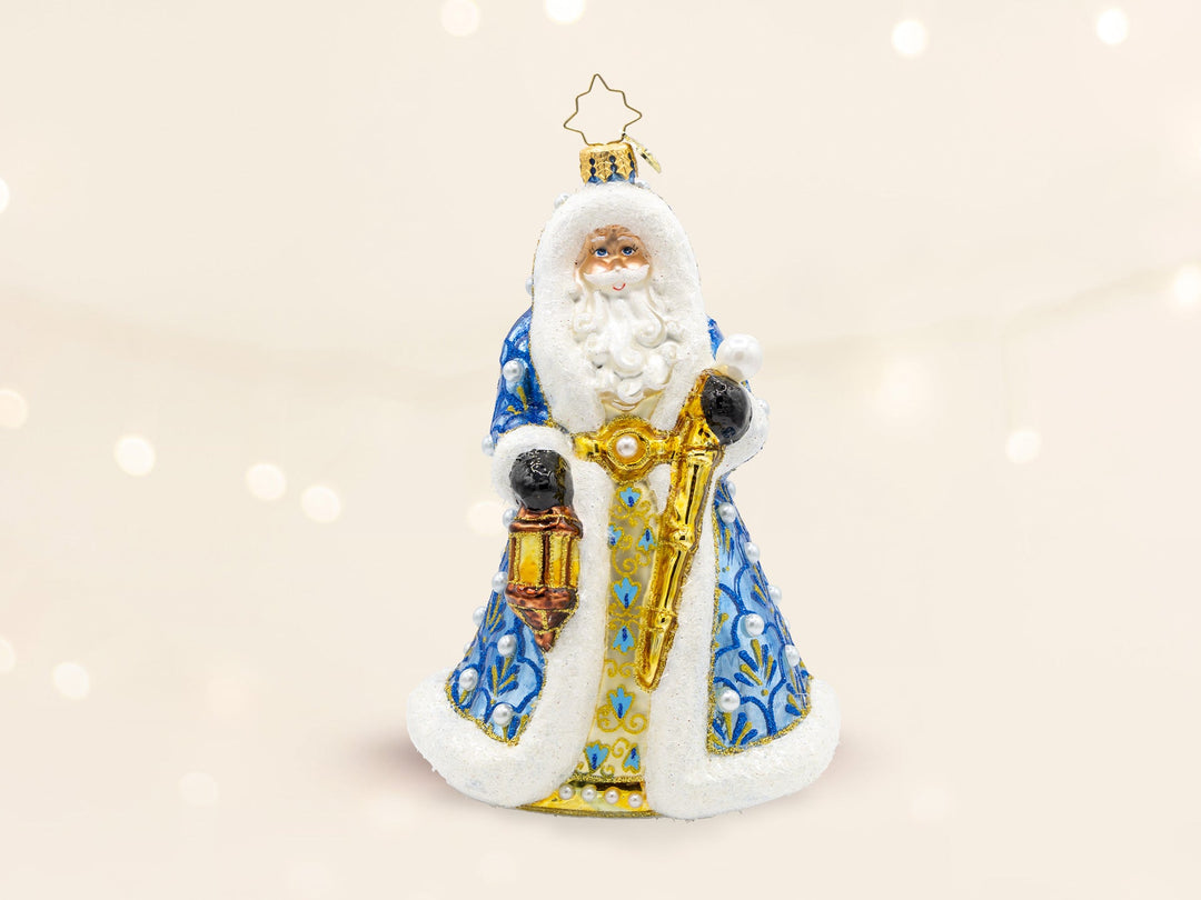 A blue hooded robed santa ornament holding a gold lattern and a gold cane.