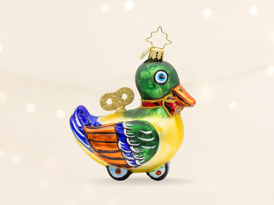 A colorful green, yellow, and blue wind up duck ornament toy on wheels.