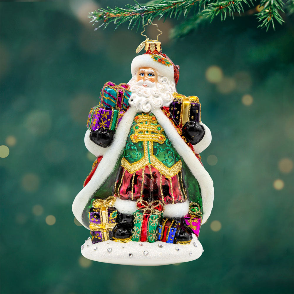 A Santa For All Seasons ornament. Santa in his intricately detailed satin coat surrounded by gifts galore. View of front.