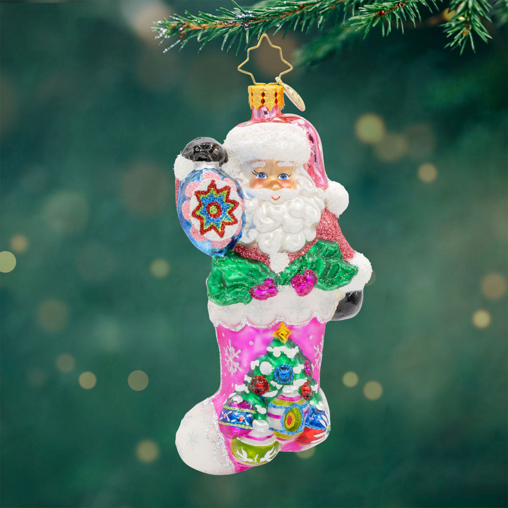 Santa's Stocking Stuffer ornament. Santa wears a shimmering pink suit and glittery hat. A colorful assortment of shiny brite ornaments adorn the stocking. View of front.