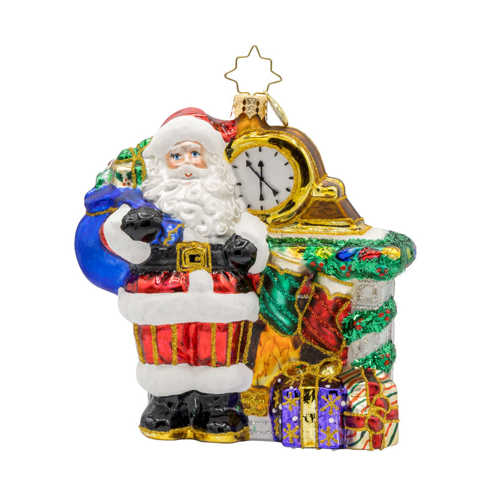 A Warm Santa by Fireplace ornament. Santa is taking a break, enjoying a cozy fire surrounded by festive goodies. View of front.