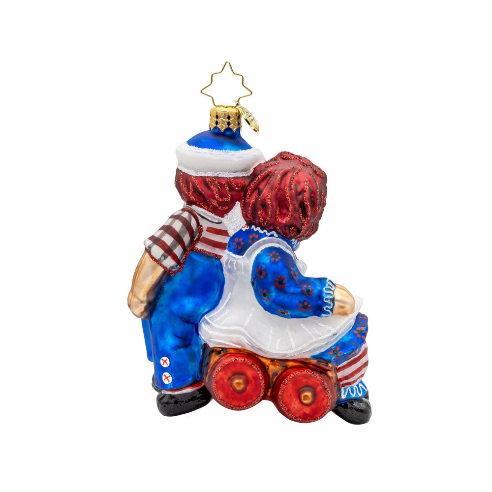 Raggedy Wagon Ride ornament. Raggedy Ann and Andy sit on a red wagon together. View of back.