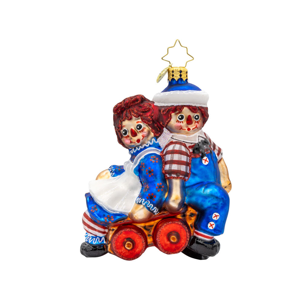 Raggedy Wagon Ride ornament. Raggedy Ann and Andy sit on a red wagon together. View of front.