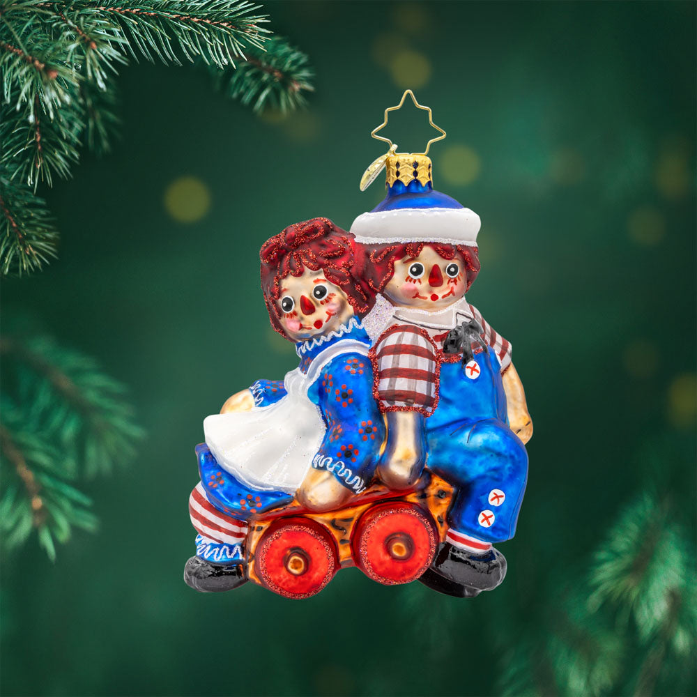Raggedy Wagon Ride ornament. Raggedy Ann and Andy sit on a red wagon together. View of front.