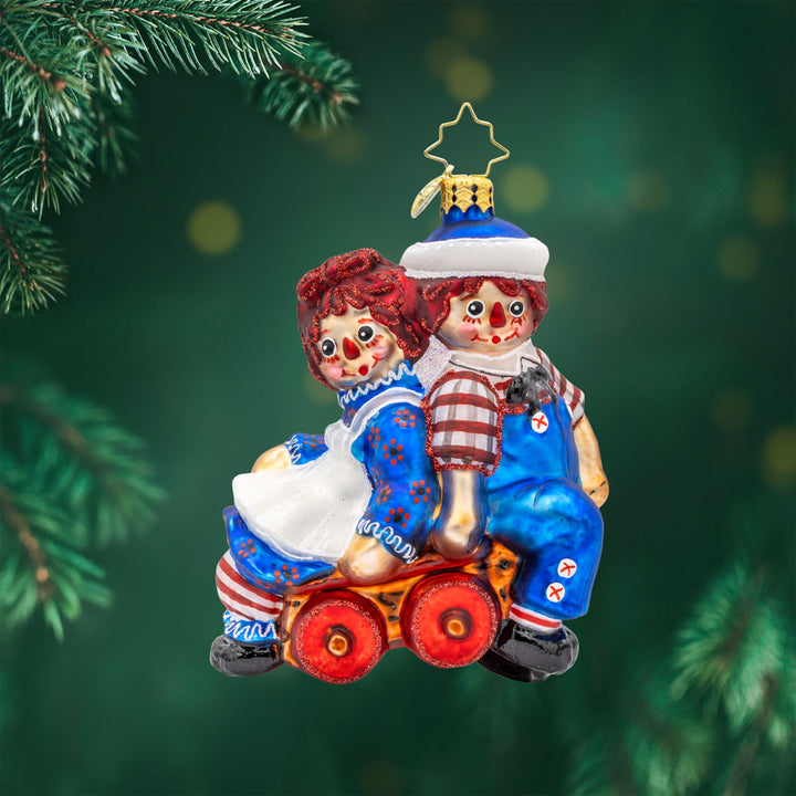Raggedy Wagon Ride ornament. Raggedy Ann and Andy sit on a red wagon together. View of front.