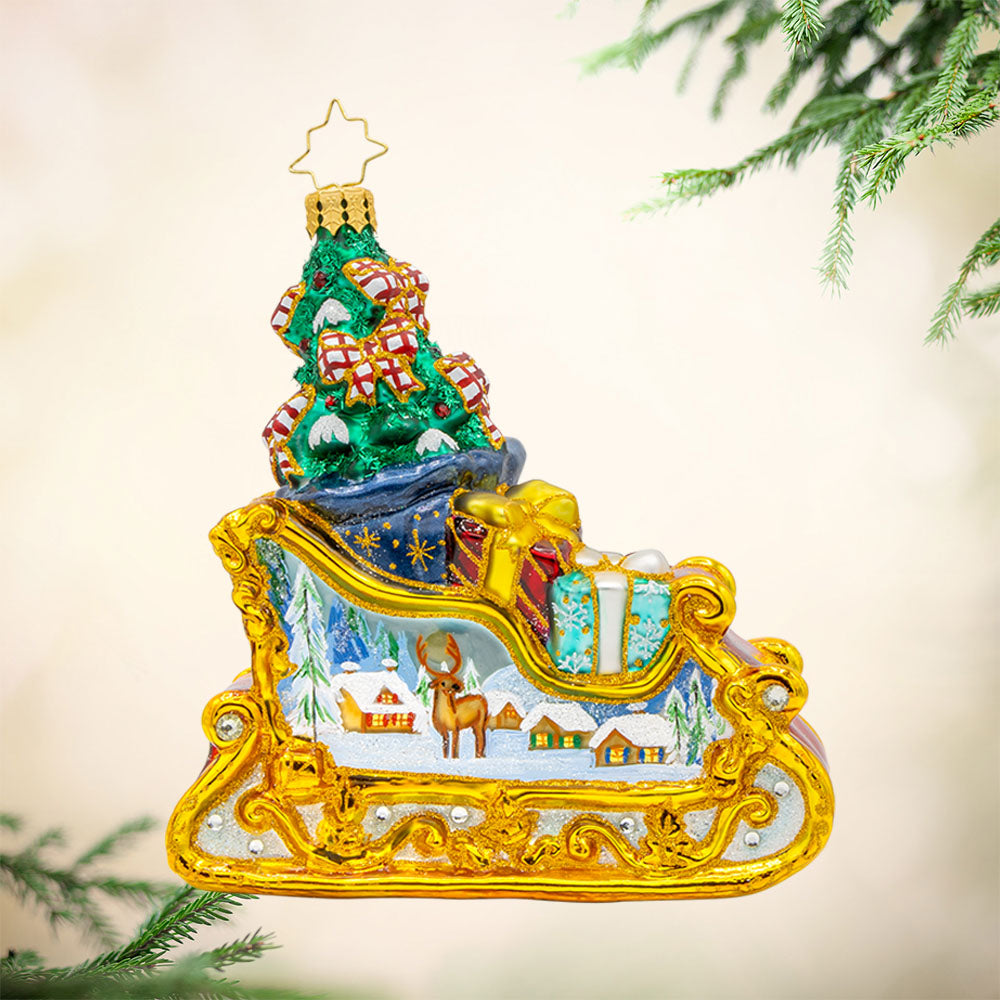 Enchanted Holiday Sleigh ornament. A beautifully crafted sleigh with intricate details, shimmering satin bows, and a hand-painted winter scene. View of left side.