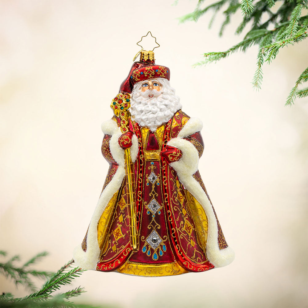 Years In the Making Nick ornament. Santa dons a deep satin red coat and a shimmering gold staff. The intricate patterns on his coat and the attached gems add a touch of opulence and elegance. View of front.