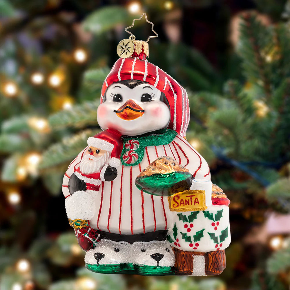 Ornament Description - Ready For Santa: Dressed in his festive PJs and stocking cap, this adorable penguin pal is eagerly awaiting Christmas morning – he even baked cookies for Santa!