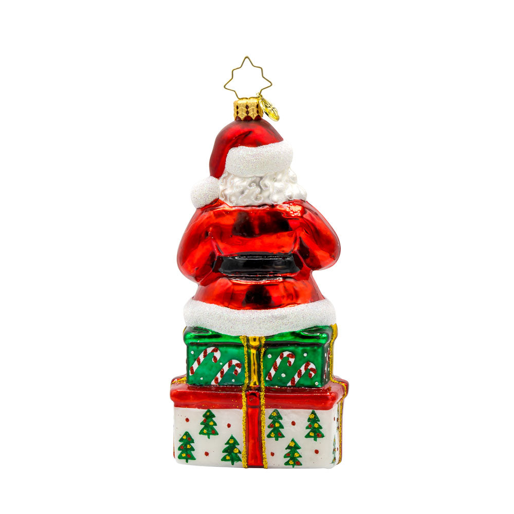 Kris Kringle's Cookie Break ornament. Santa takes a cookie break, perched atop a glittering present. View of back.