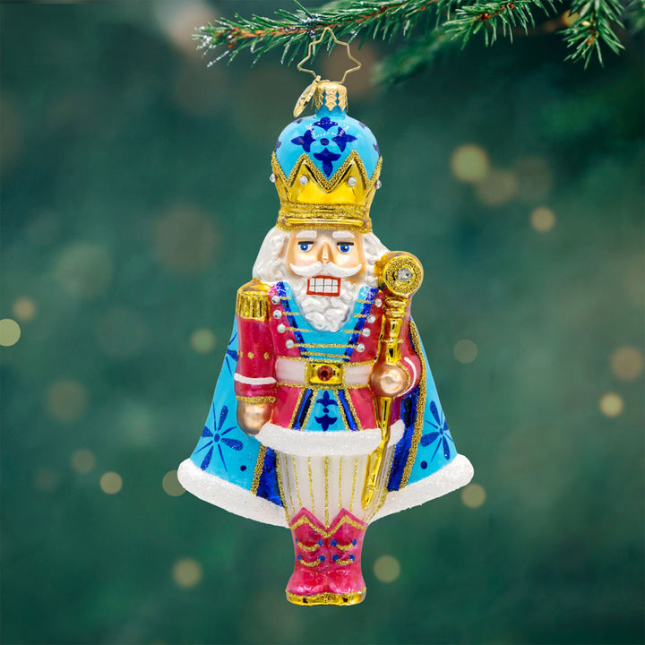 Choral Charm Nutcracker ornament. With his dazzling crown, shimmering cape, and colorful outfit. View of front. 