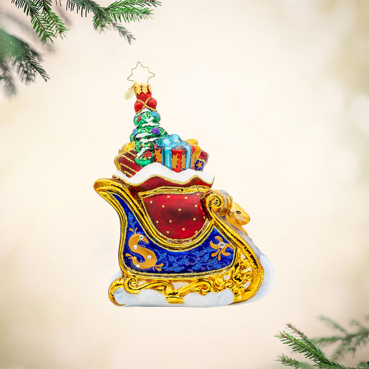 Celebratory Sleighride ornament. Royal Blue and gold sleigh, adorned with shimmering jewels and regal ribbons. View of front. 