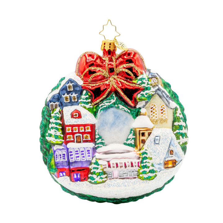 Christmas Village Charm ornament. Charming houses, twinkling lights, and a snowy scene topped with a red bow. View of back.