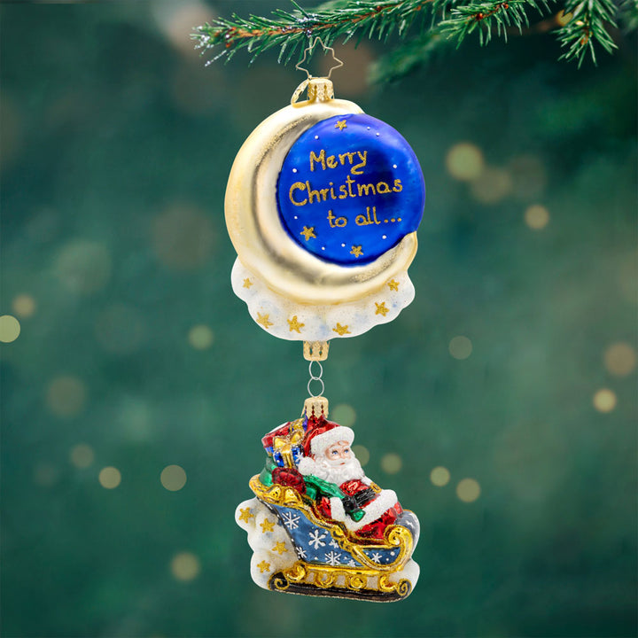 Moonlight Sleigh Ride ornament. With his shimmering moon, twinkling stars, and festive sleigh, Santa soars through the night, delivering presents to children around the world. "Merry Christmas to all..." written on front. View of front.
