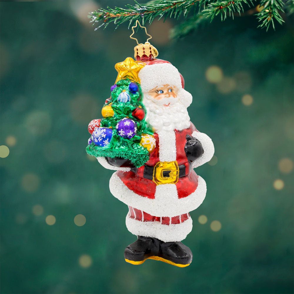 Tree-Totin' Santa ornament. Santa carries a mini decorated Christmas tree.  View of front.