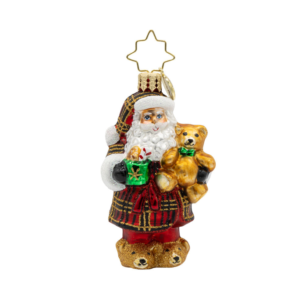 Sweet Slumber Treat Gem ornament. Santa is seen dressed in a plaid red, gold, and black robe. Tedd bear in hand and a mug of hot cocoa in the other. View of front. 