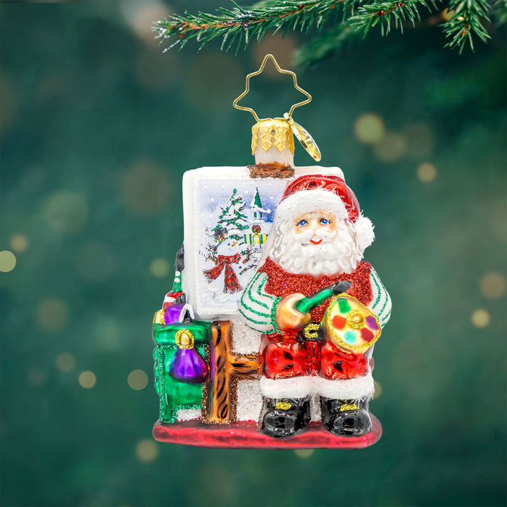 Pretty As A Picture Gem ornament. Santa is seen here painting a Christmas scene on a canvas. View of front.