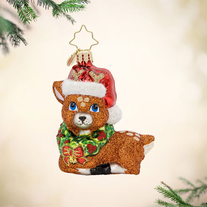 Fawning Over the Holidays Gem ornament. A laying fawn crowned with a wreath and Santa hat. View of front. 