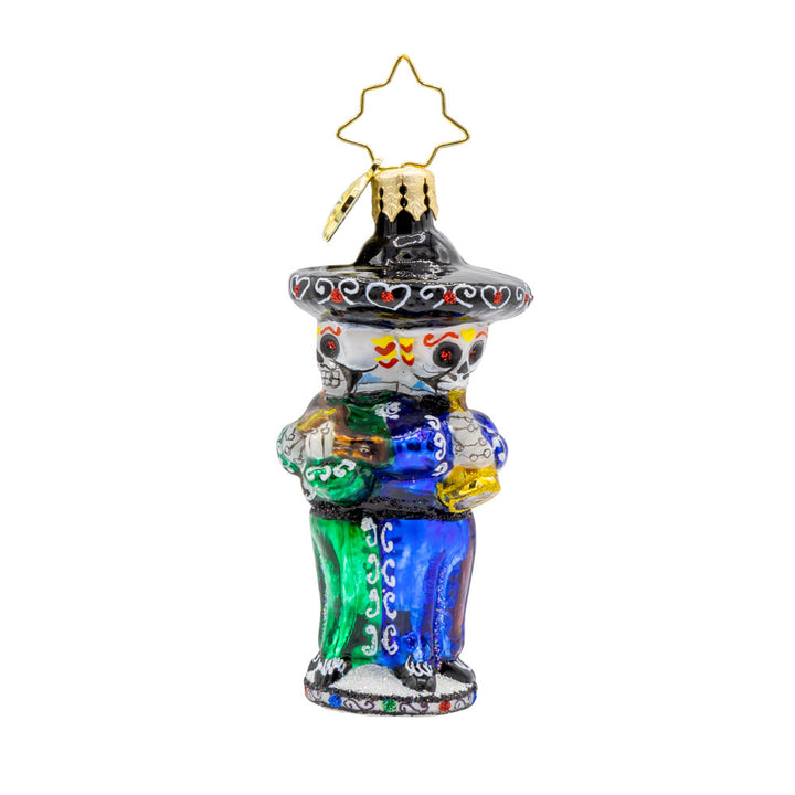 Skeleton Serenade Gem ornament. A band of three skeletons, instruments in hand, sombreros on head, dressed in festive green, red, and blues. View of back.