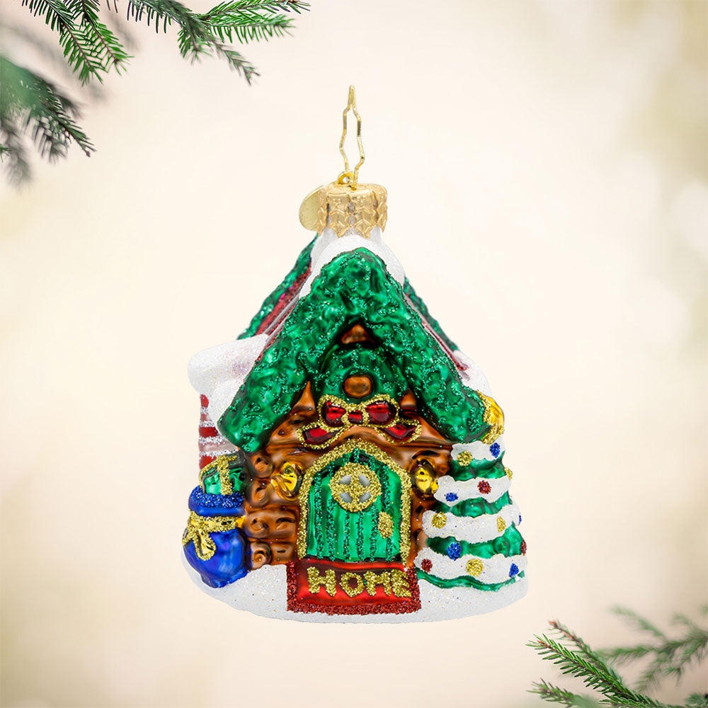 Hidden Woods Hideaway Gem ornament. A log cabin covered in snow and festive cheer. View of front. 