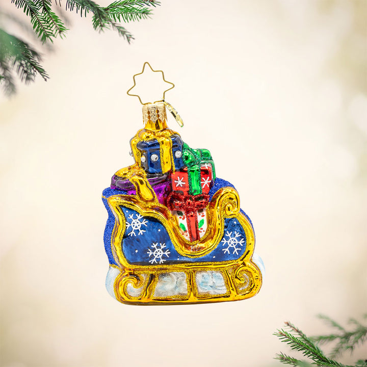 Starry Night Sleigh Gem ornament. A blue sleigh with gold trim, piled high with gifts. View of front. 