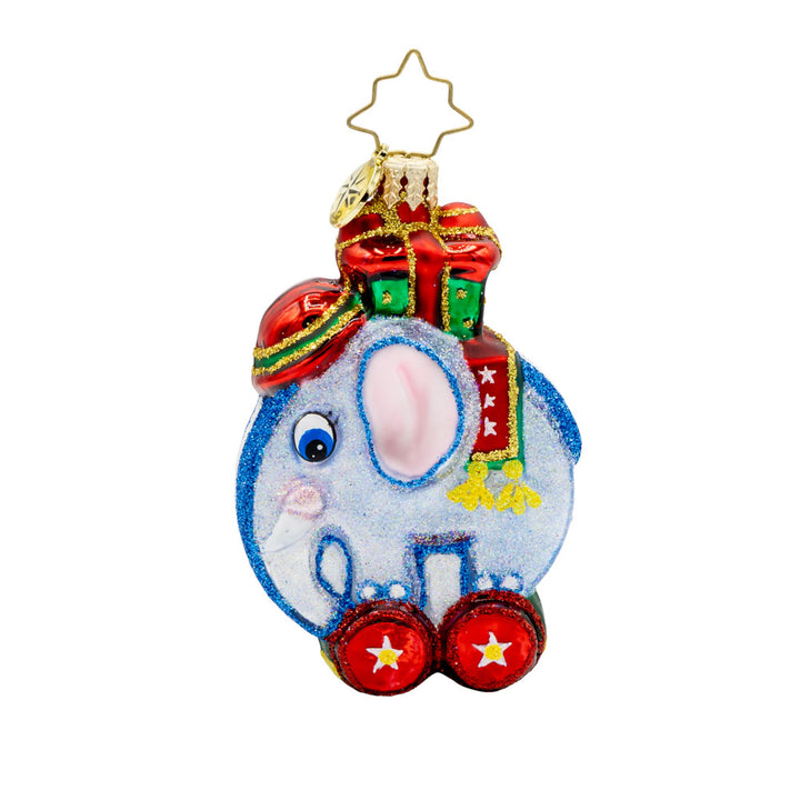 Tiny Trunk Traveler Gem ornament. A blue toy elephant with a gift atop its back, standing on two red wheels. View of back.