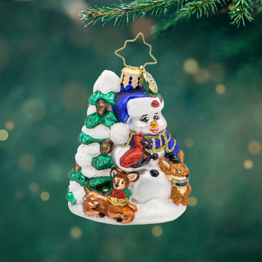 Wintery Pals Gem ornament. A snowman is seen with his forest friends in front of a pine tree covered in snow. View of front. 