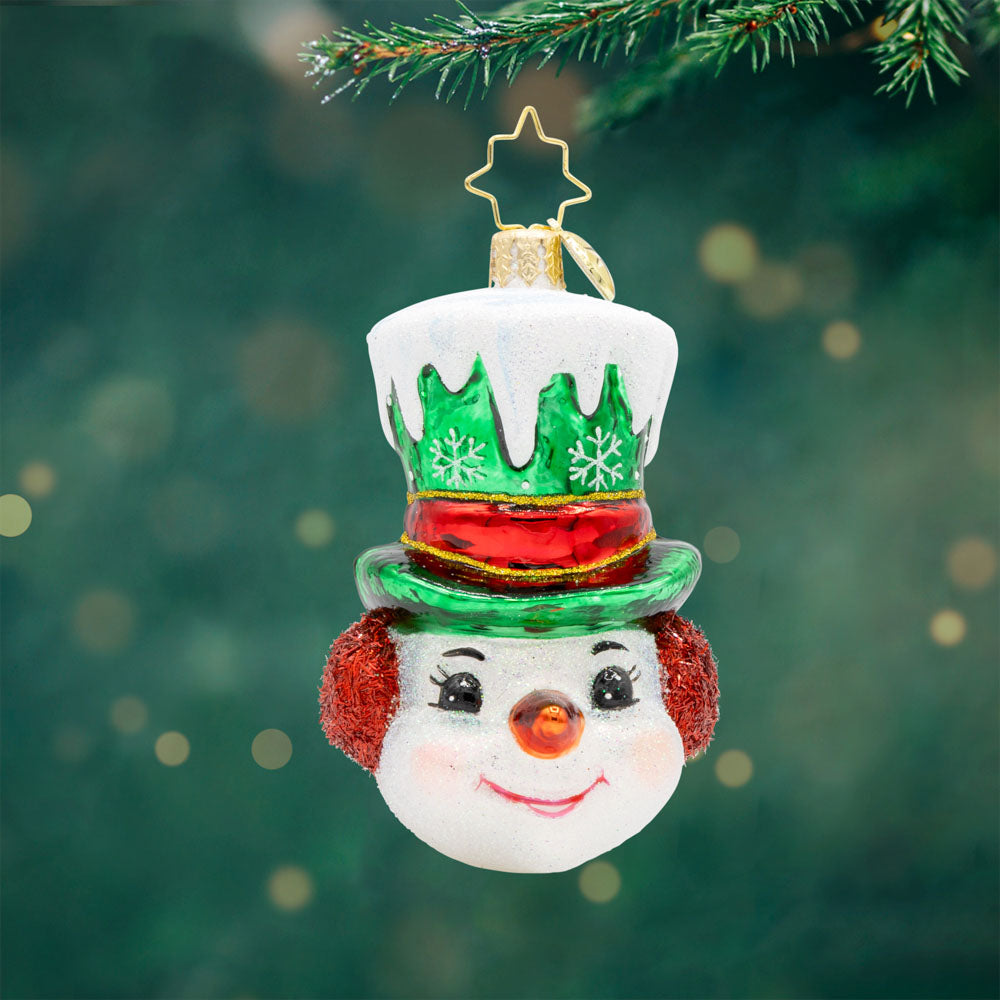 Top Hat Tidings Gem ornament. This snowman wears a green top hat, covered in snow with a red ribbon around it. View of front. 