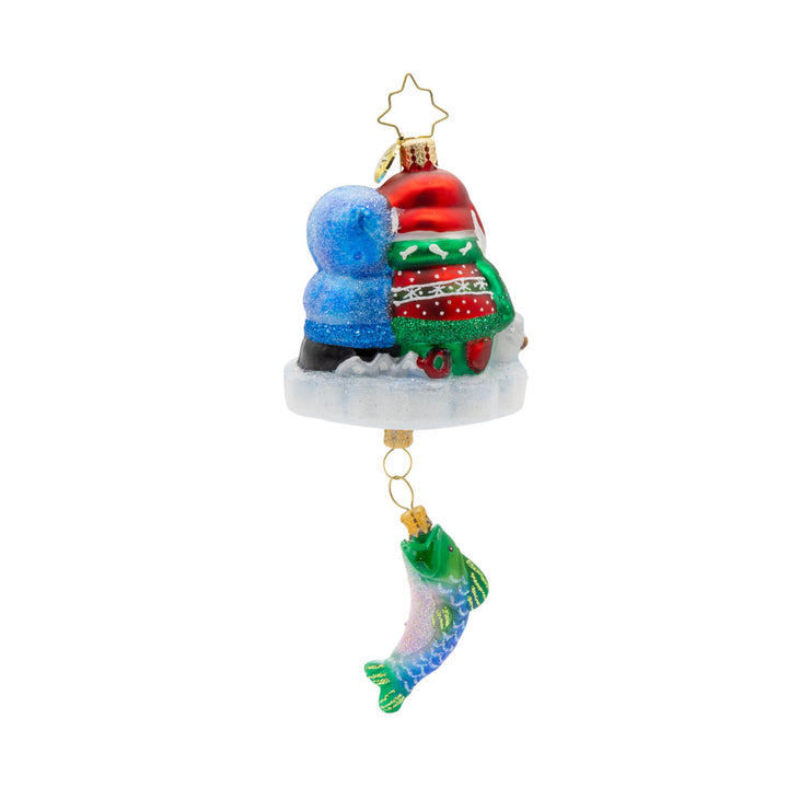 Ice Fishing Snow Pals Gem ornament. A snowman and penguin sit bundled up on a block of ice with a fishing pole. A fish dangles below. View of back.