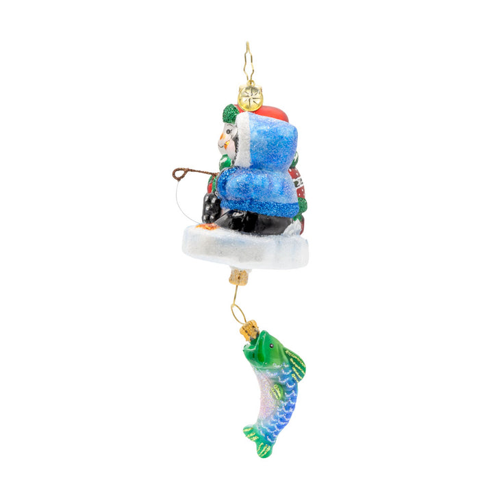 Ice Fishing Snow Pals Gem ornament. A snowman and penguin sit bundled up on a block of ice with a fishing pole. A fish dangles below. View of right side.