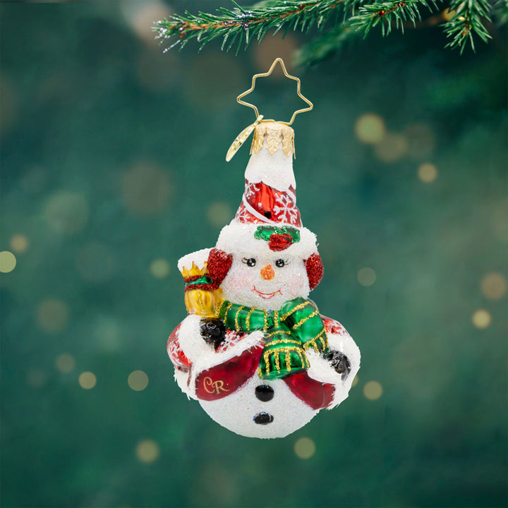 Swept Up Snowman Gem ornament. A snowman donned in a red and snowflake flecked coat with a broom in hand. View of front.  
