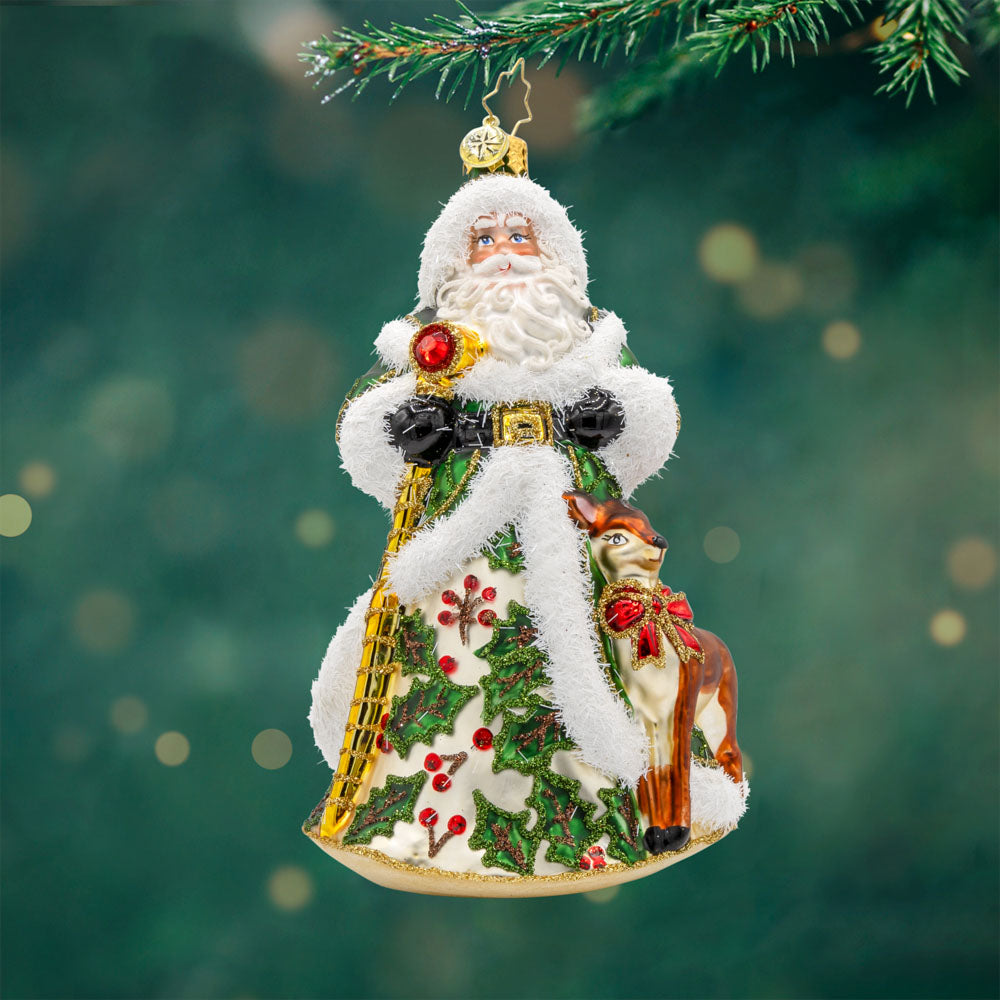 Deerly Beloved Santa ornament. Santa and his reindeer are dressed to impress. Santa dons a green hand-painted coat of holly. The reindeer has a red bow around its neck. View of front. 