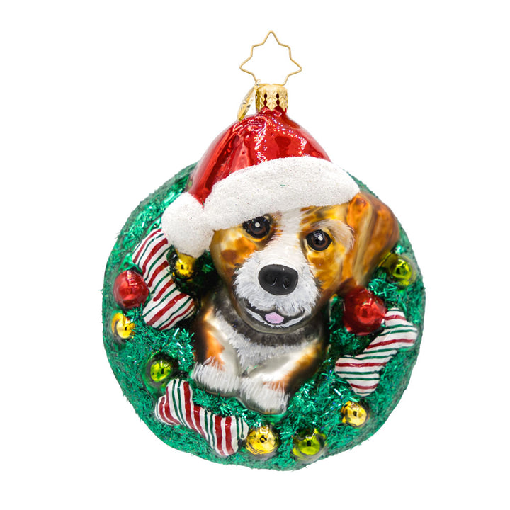 Merry Dogmas ornament. Features a pup wearing a Santa hat, encircled by a wreath and festive bones. View of front. 