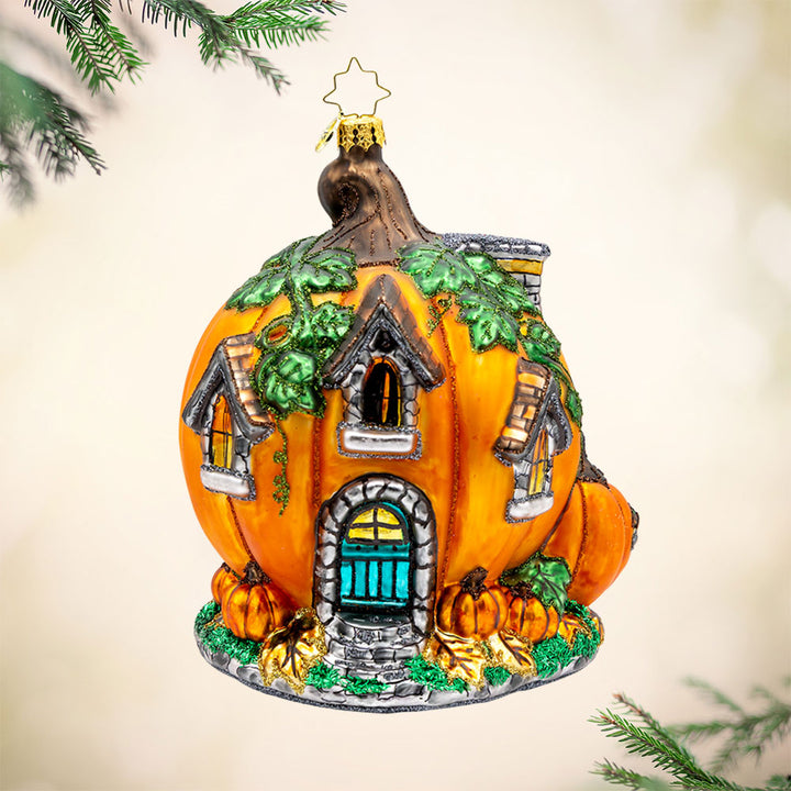 Pumpkin Patch Abode Ornament. Featuring a vibrant pumpkin exterior with windows, a whimsical door, and a leafy roof. View of front.