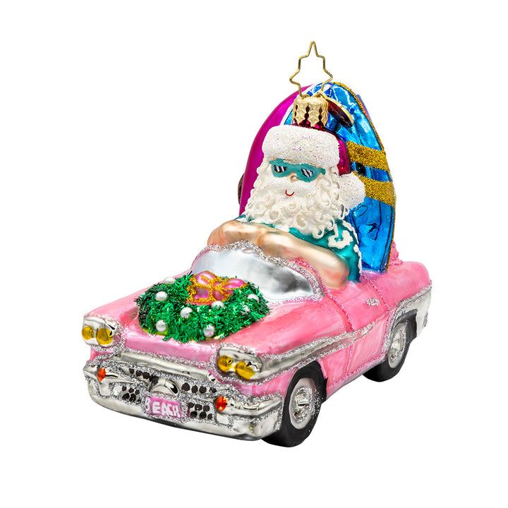 Santa's Coastal Christmas Ride ornament. Santa drives a pink car with his surfboard, sunglasses, and beach gear. View of right side angle.