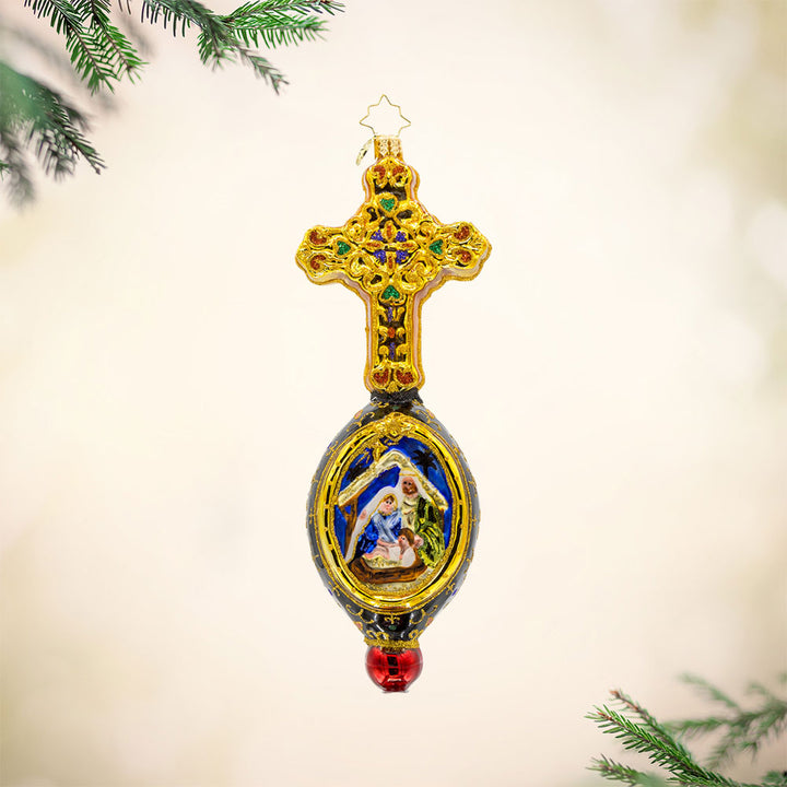 This exquisite ornament showcases a hand-painted nativity scene framed by a resplendent cross. Adorned with shimmering gems and vibrant colors. View of front.