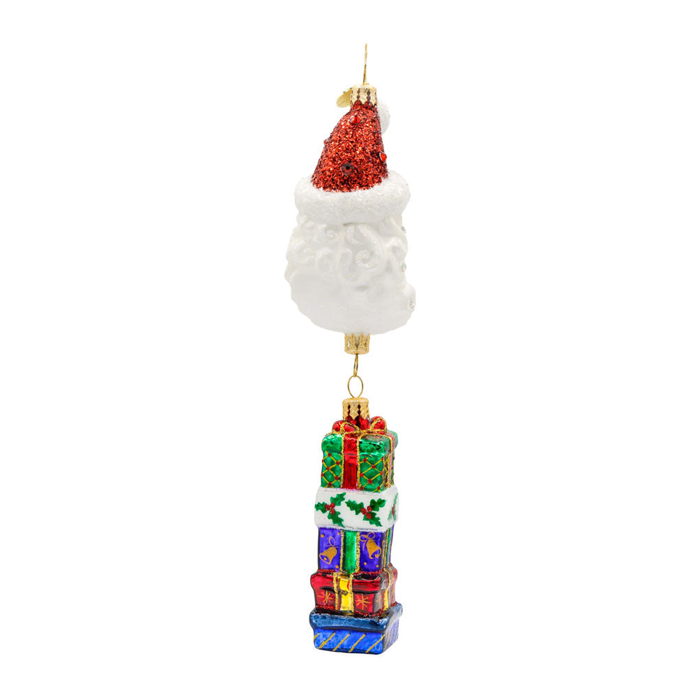 Lunar Treasures ornament. Santa's head in the shape of a crescent moon, with a stack of gifts dangling below. View of left side.