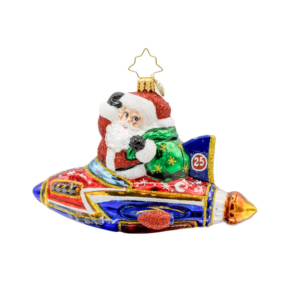 St. Nick's Yuletide Blast ornament. Santa rides in a rocket ship with a green gift sack in hand. View of front. 