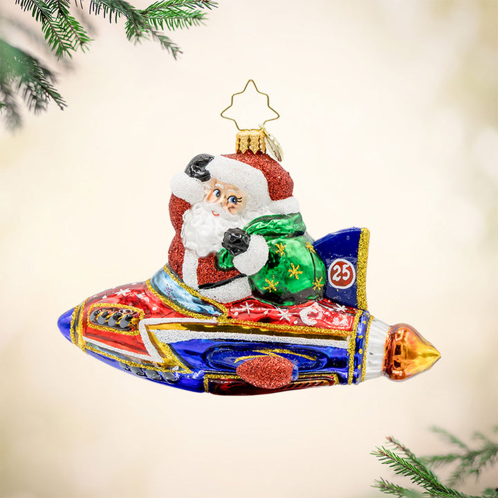 St. Nick's Yuletide Blast ornament. Santa rides in a rocket ship with a green gift sack in hand. View of front. 