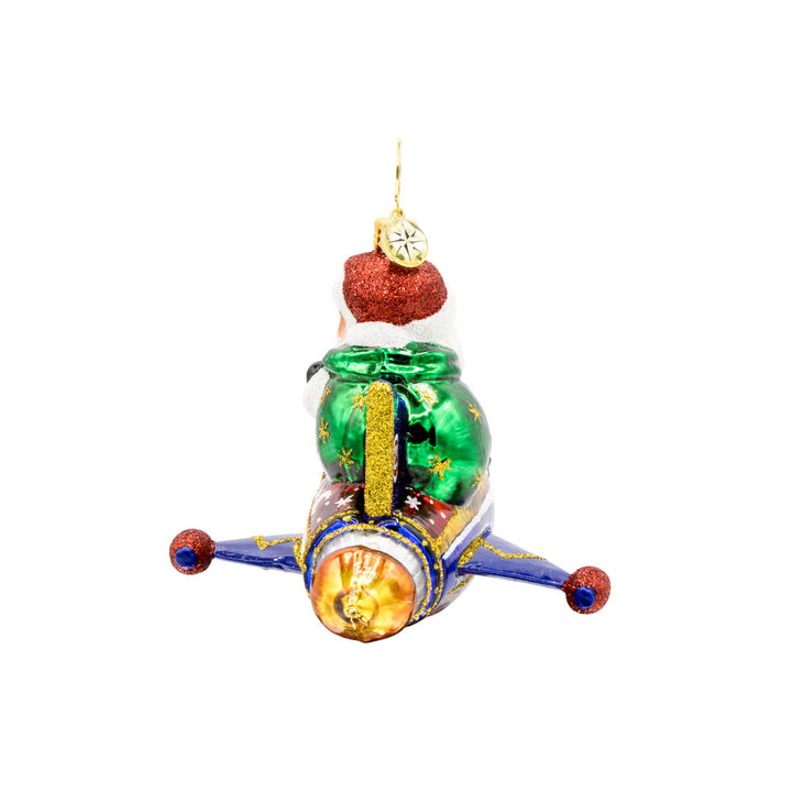 St. Nick's Yuletide Blast ornament. Santa rides in a rocket ship with a green gift sack in hand. View of right side.