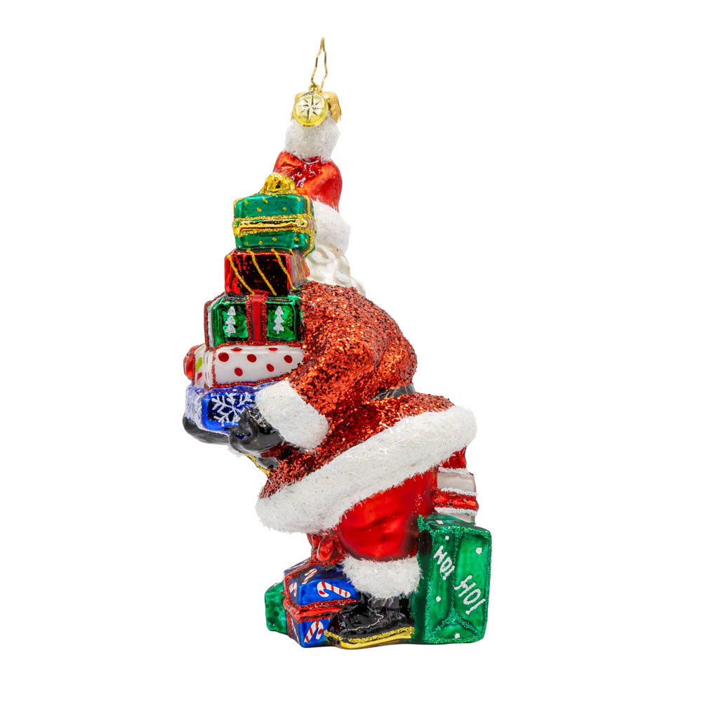 Santa's Surprise Stash ornament.  Features Santa carrying a tower of  festive presents. View of right side.
