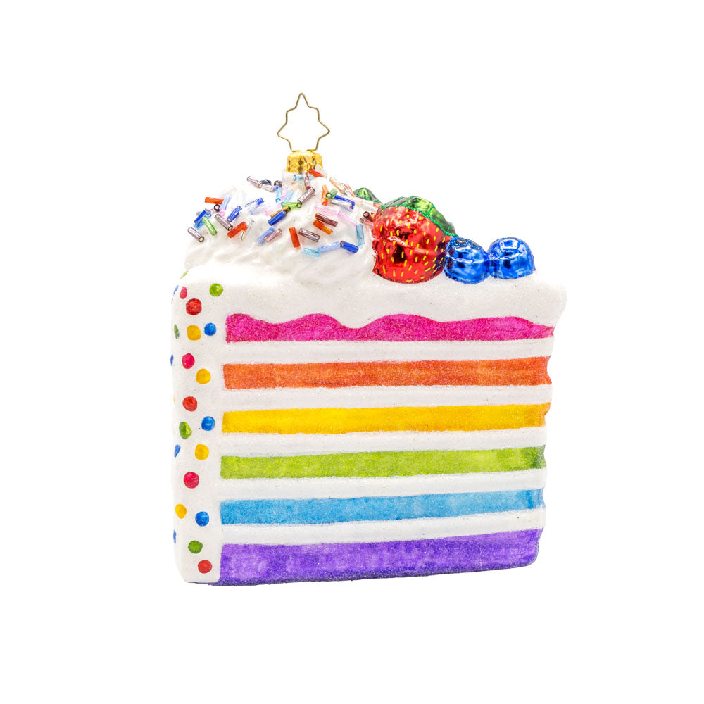 Slice of Joy ornament. A tall slice of rainbow layered cake with sprinkles and fruit on top. View of front. 