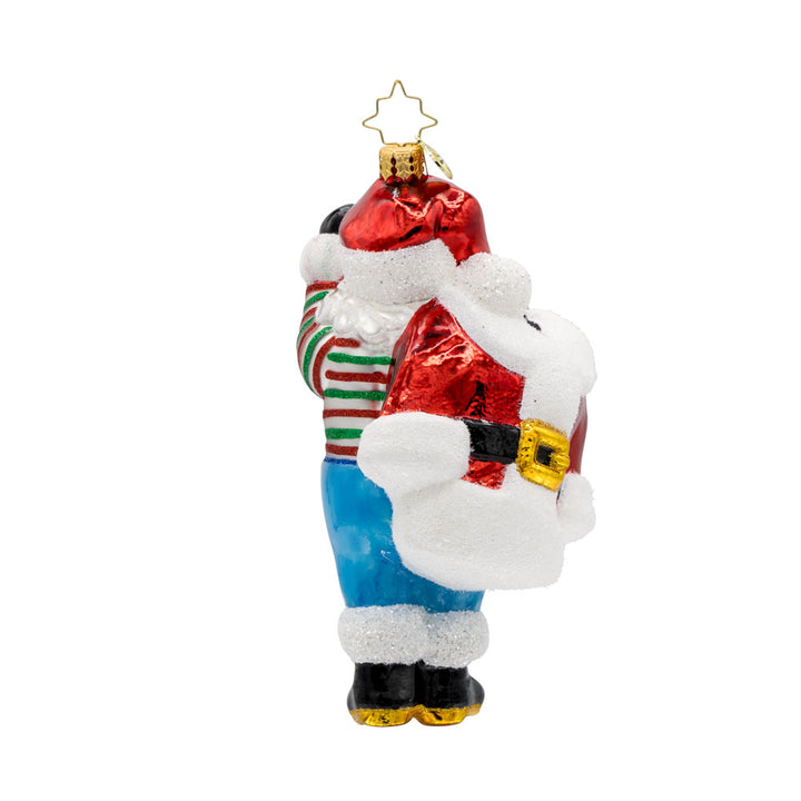 Santa's Wardrobe Change ornament. Santa is holding his freshly tailored suit, with a twinkle in his eye and a mischievous grin. View of back.