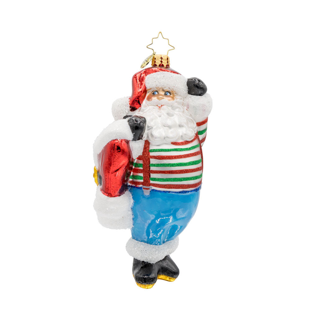 Santa's Wardrobe Change ornament. Santa is holding his freshly tailored suit, with a twinkle in his eye and a mischievous grin. View of front. 