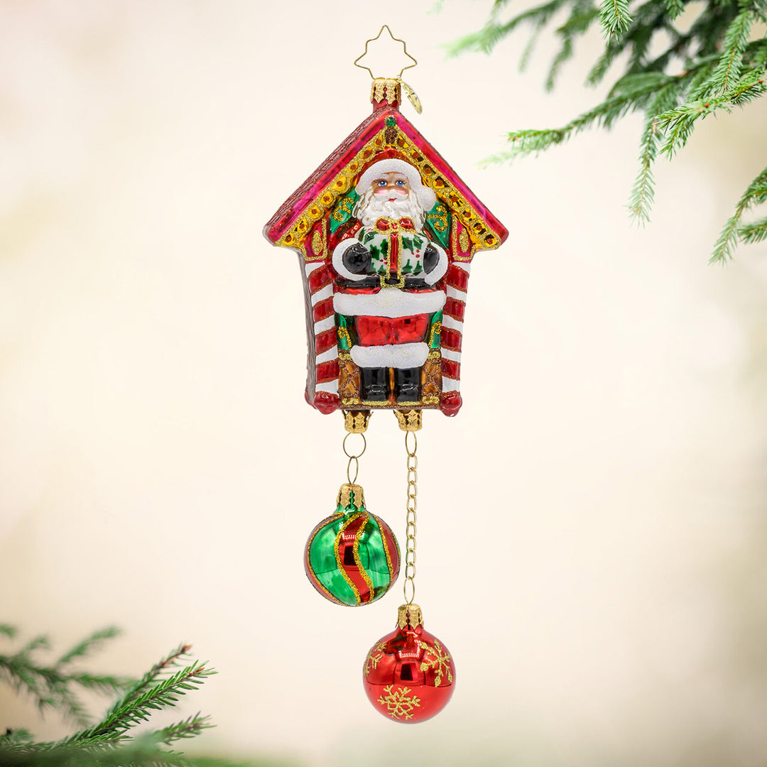 Jolly Timekeeper ornament. Santa holds a gift in the center of this festive take on a cuckoo clock. View of front. 